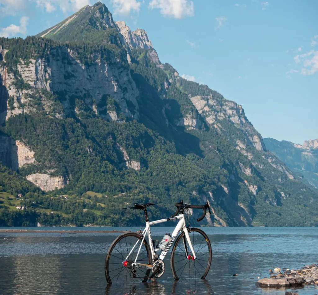 Bicicleta de carrera mitad en agua con montañas en segundo plano.