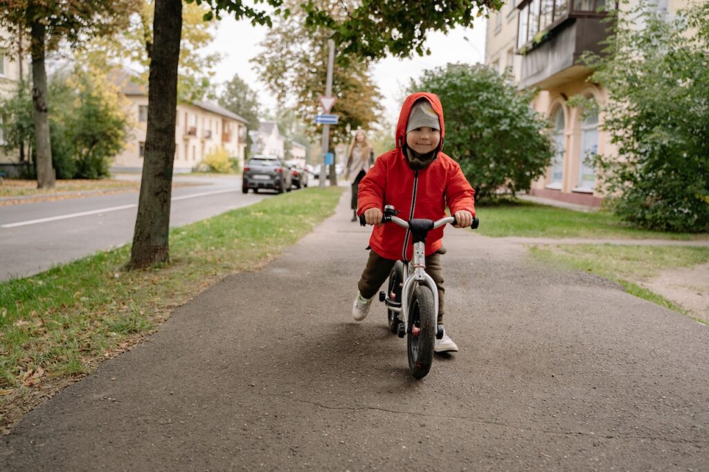 Enfant souriant courant sur un vélo d'équilibre