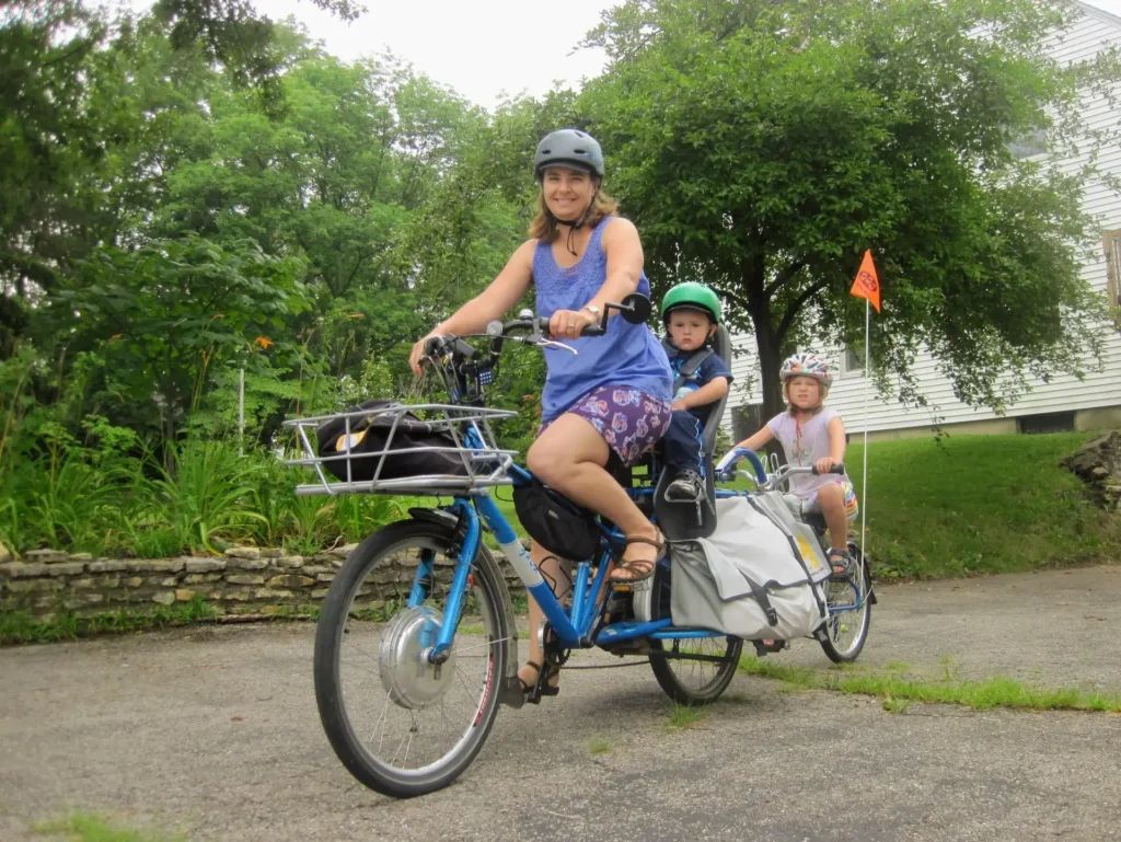 mãe a equilibrar uma bicicleta em tandem com duas filhas