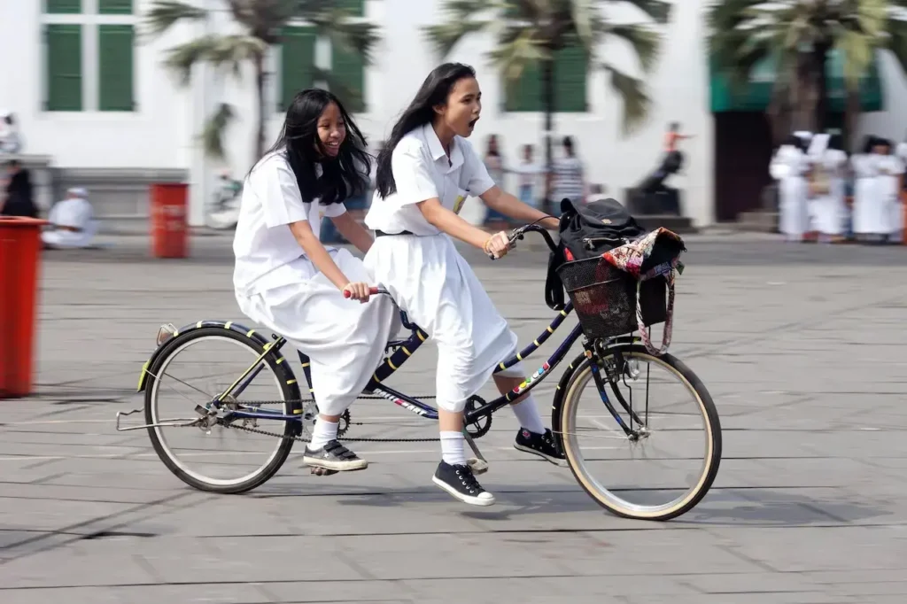 dua saudara perempuan menyeimbangkan diri di atas sepeda tandem